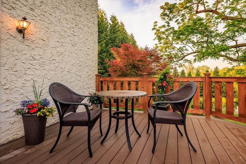 Back deck with bistro seating overlooking the cottage lawn and trees