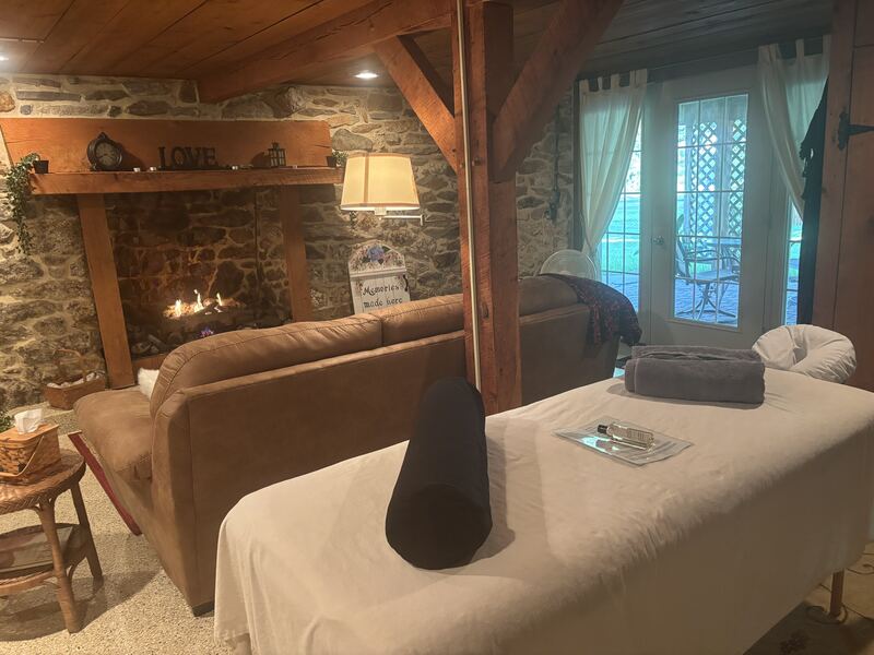 Massage table beside the couch and stone fireplace in the cozy basement of the cottage