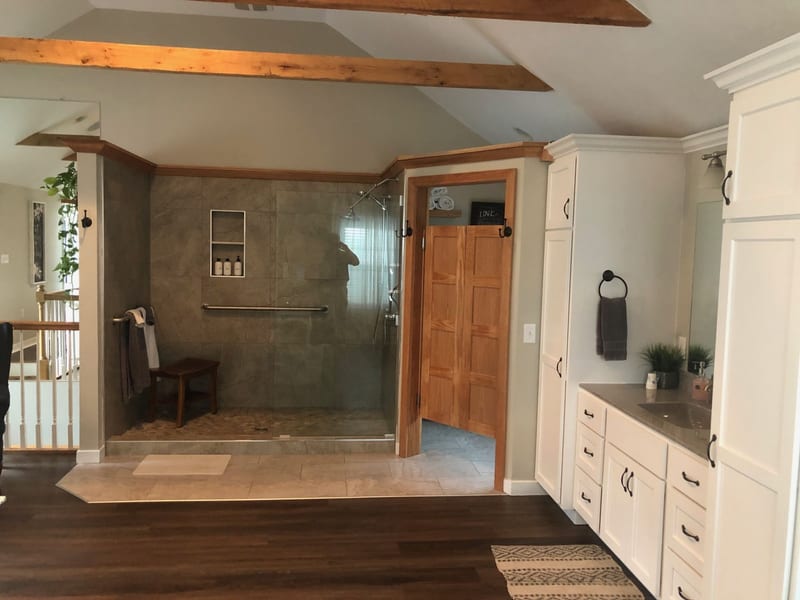 Spacious tiled walk-in shower with a teak bench in the master bathroom