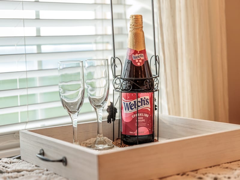 Welcome tray with two flutes and a bottle of sparkling red grape juice by the window